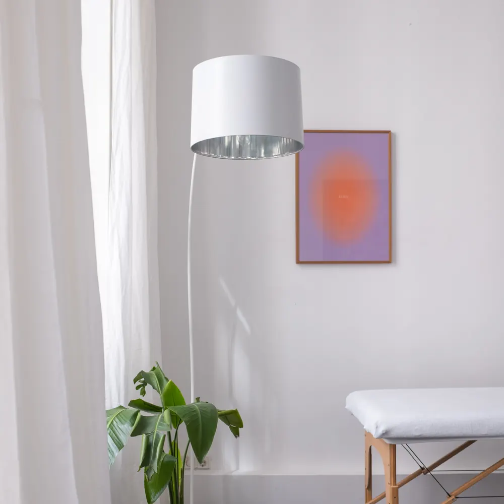 Heller Praxisraum mit Stehlampe, Pflanze und Behandlungsliege